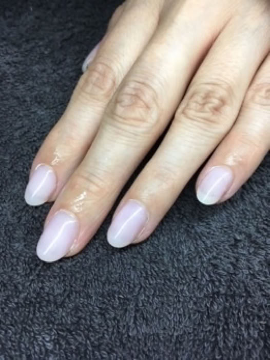 kurze schöne milchige Gelmodellage an linker Frauen Hand