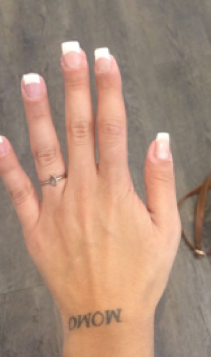 tätowierte schöne Hand mit Gelmodellage und French. Zeit sparen durch mit gel modellierten Fingernägeln.